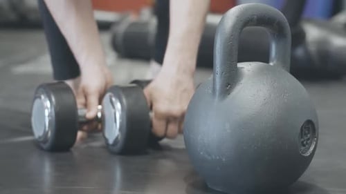 Close-up do peso na academia com esportista caucasiano desfocado pegando pesos das mãos ao fundo e