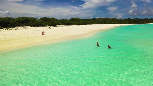 Tourists relaxing on marine tourist beach holiday by shallow ocean and white sand background of the