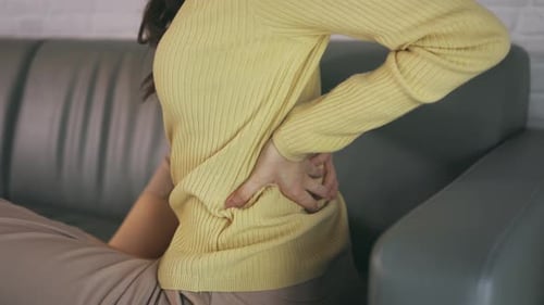 Woman Massaging Lower Back Pain on Sofa