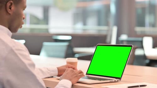 African Businessman Using Laptop with Green Chroma Screen