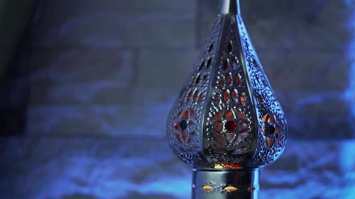 Lampe im orientalischen Stil mit brennender Kerze auf hellblauem Hintergrund