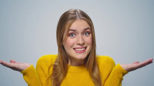 Portrait of Smiling Attractive Woman Shrugging Shoulders on Grey Background