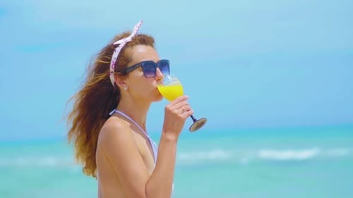 Portrait of the Young Cheerful Attractive Girl, Drinking Orange Juice and Smiling