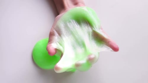 Hand Playing with Textured Slime Stretching the Gooey Substance