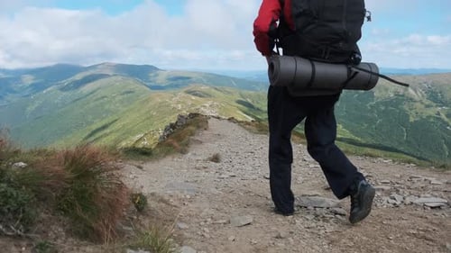 Tourist with a Backpack Goes Down Along the Stone Mountain Trail on the Hill