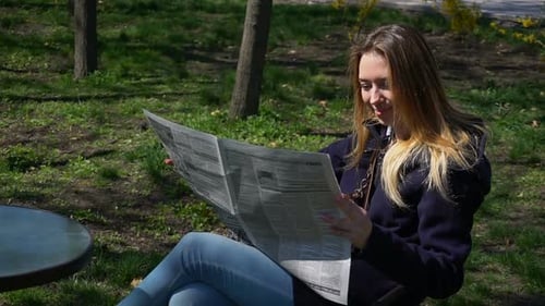 Wunderschönes Mädchen liest Klatsch in der Zeitung.