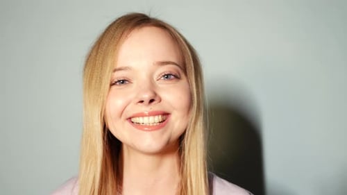 Smiling Blonde Woman in Front of Wall