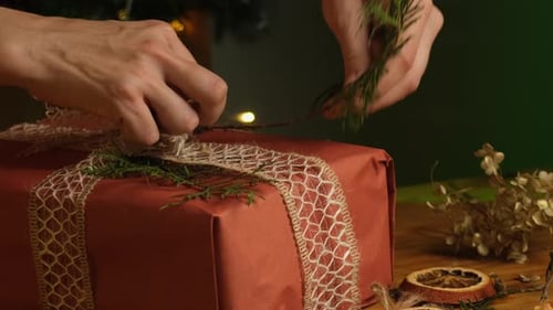 Hands Decorate a Christmas Gift with Greenery