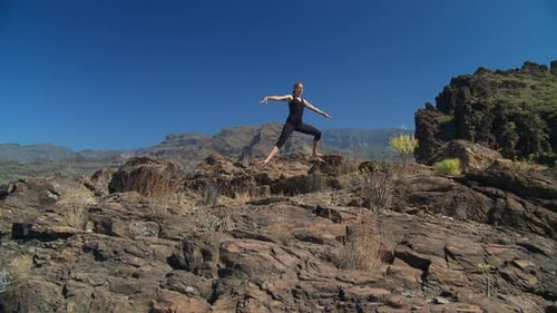 Active Woman Doing Yoga Atop Rocky Mountain