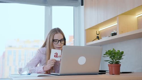 Young woman teacher shows pictures with the alphabet.Teaching children at school online