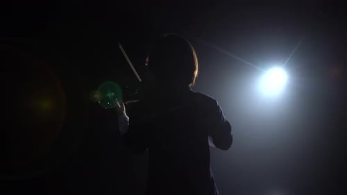 Professional Playing the Violin in a Dark Studio with a Lantern From It Glare