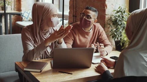 Muslim Colleagues in Face Masks Discussing Business on Lunch in Cafe