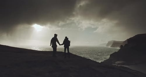 Couple walk hand in hand along hilltop