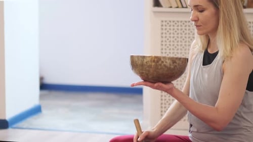 Woman Plays Singing Bowl for Meditation Indoors