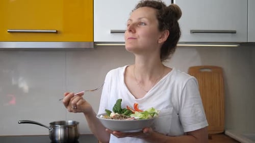 Woman Enjoys Healthy Salad in Modern Kitchen