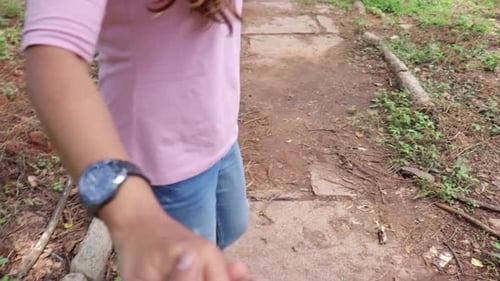 Woman Leading Partner Down Forest Path Holding Hands