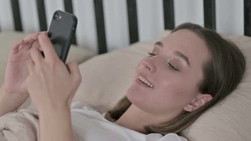Woman Relaxing in Bed Using Smartphone