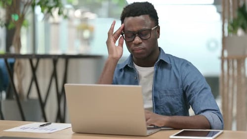 Man with Headache Massaging Forehead at Desk