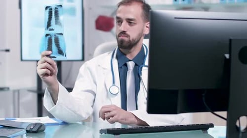 Doctor Examines Carefully an X Ray with Lungs