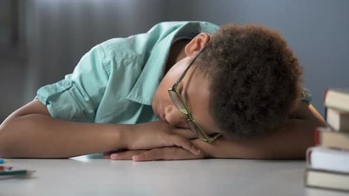 Boy Sleeping with Head on Arms at Table
