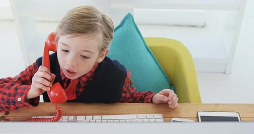 Boy Talking on Retro Telephone at Desk