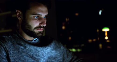 Young Adult Using Computer in Urban Setting at Night