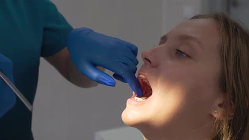 El ortodoncista retira la banda elástica rosa de los aparatos ortopédicos con una herramienta