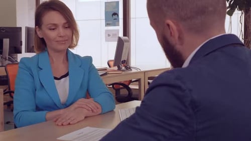 Smiling Woman and Man Shake Hands at Meeting