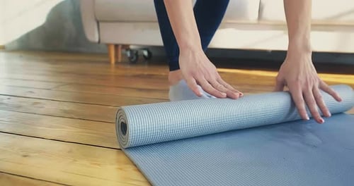 Woman Unrolling Gray Yoga Mat at Home