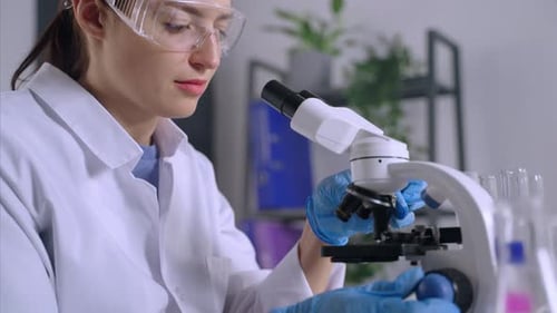 Woman Adjusting Microscope in Science Laboratory