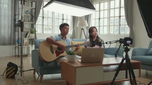 Niños asiáticos tocando la guitarra y cantando una canción mientras transmiten