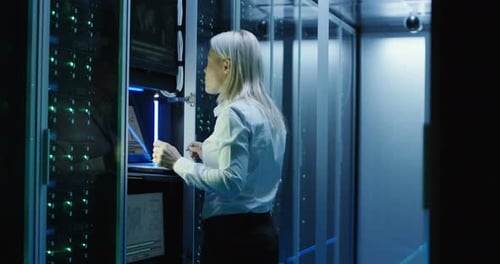Female Technician Works on a Laptop in a Data Center