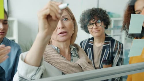 Team Discussing Strategy Writing on Glass Board