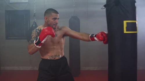 Athletic Man Training Boxing with Punching Bag