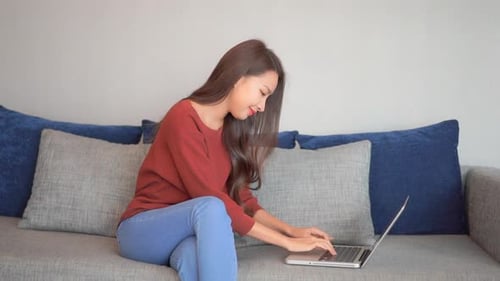 Brunette Woman Typing on Laptop Computer on Couch