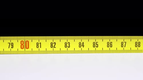 Tape Measure Retracts Close Up On White Surface