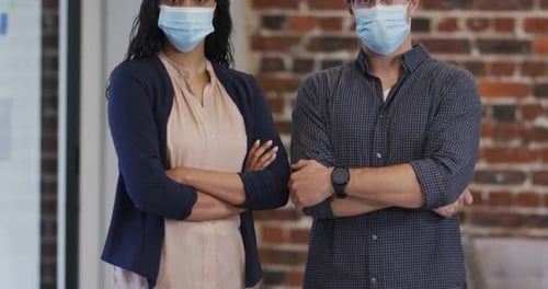 Portrait of man and woman wearing face masks in office
