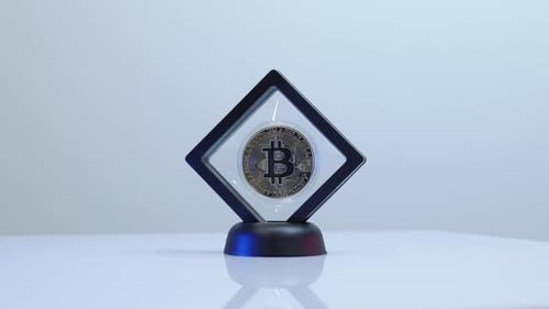 Einzelner Bitcoin im Rahmen dreht sich langsam und reflektiert Licht. BTC-Münze ro