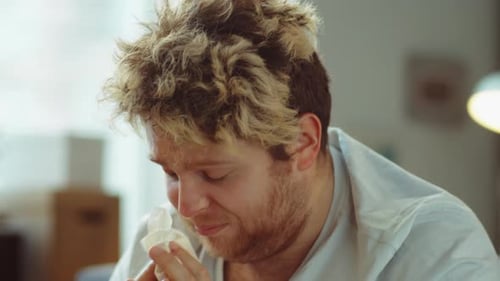 Sick Man Blowing Nose with Tissue Indoors