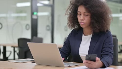 Woman Using Phone and Laptop in Office