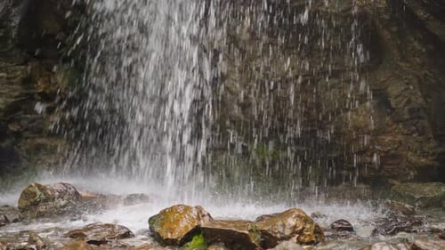 Water Jets Fall Down Into Pool with Stones at Wild Highland