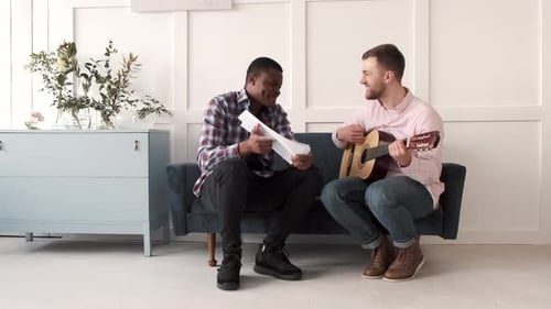 Men Play Guitar, Sing, and Enjoy Friendship Indoors