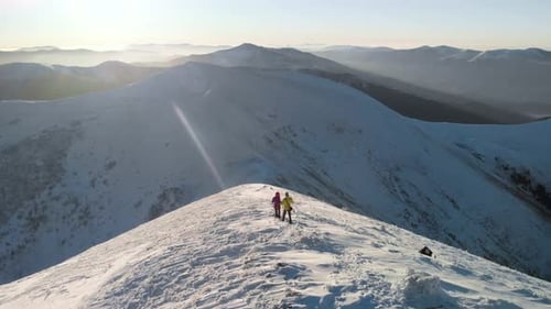 Hikers on Snowy Mountain Peak on a Sunny Day