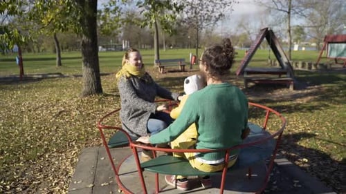 Family playing at merry-go-round in public playground, Zagreb, Croatia.