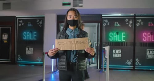 Une femme asiatique masquée proteste contre le Black Friday