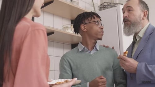 Three People Enjoying Pizza Together in Kitchen
