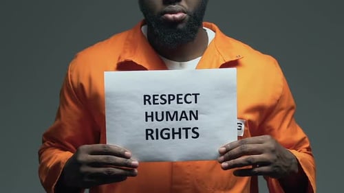 Expression sur le respect des droits de l'homme sur du carton entre les mains d'un prisonnier