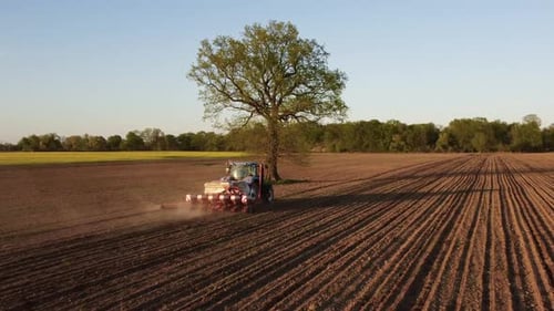 Tractor Working in Field at Sunset