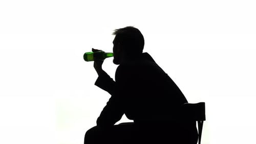 El alcohólico se sienta con una botella en las manos y bebe. Vista lateral. Fondo blanco silueta