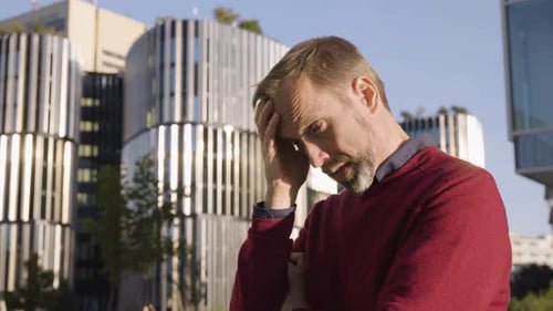 A Middleaged Handsome Caucasian Man Thinks About Something and Acts Sad in an Urban Area